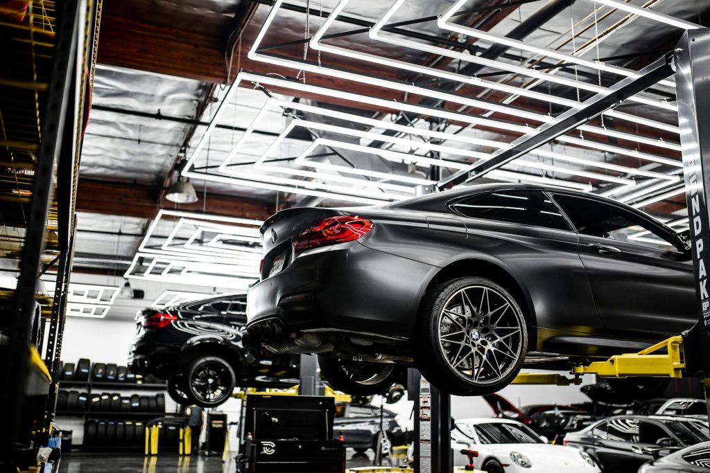 Un atelier de réparation automobile moderne présentant des véhicules sur des ponts élévateurs et un intérieur bien éclairé et organisé.