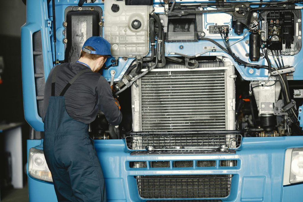 Un mécanicien en uniforme travaille sur un moteur de camion dans un atelier industriel. Idéal pour les thèmes liés à la maintenance automobile.