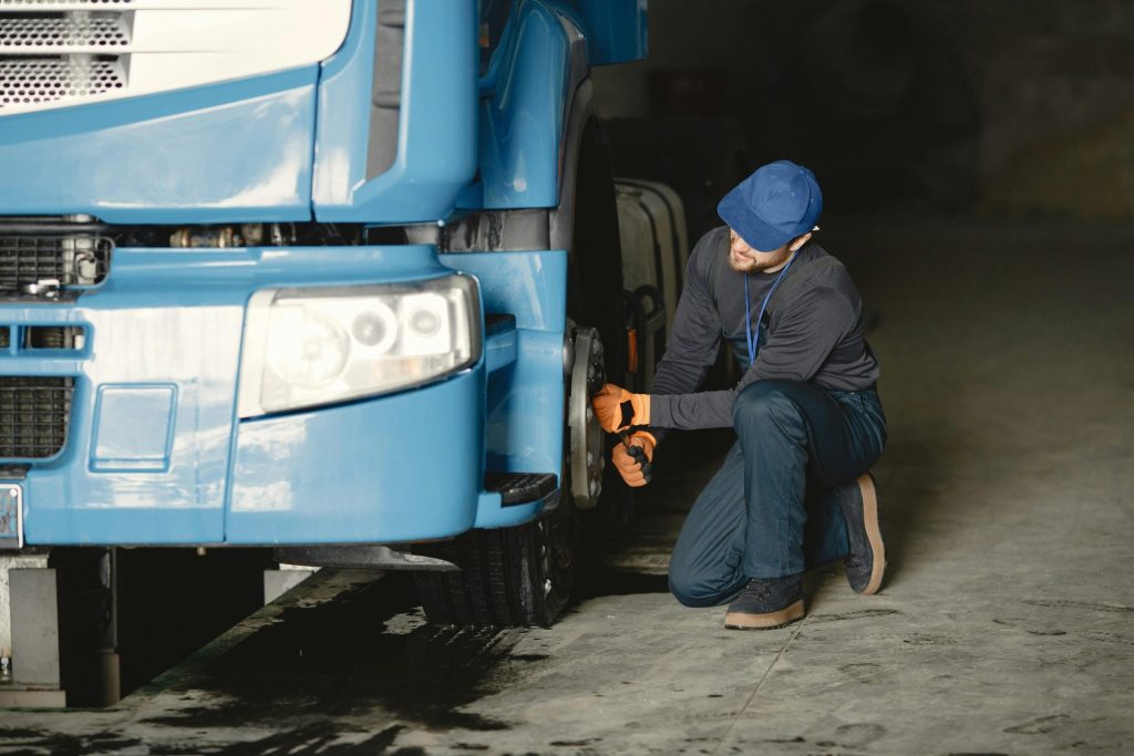 Un mécanicien répare la roue d'un camion bleu dans un garage. Entretien de véhicules industriels.